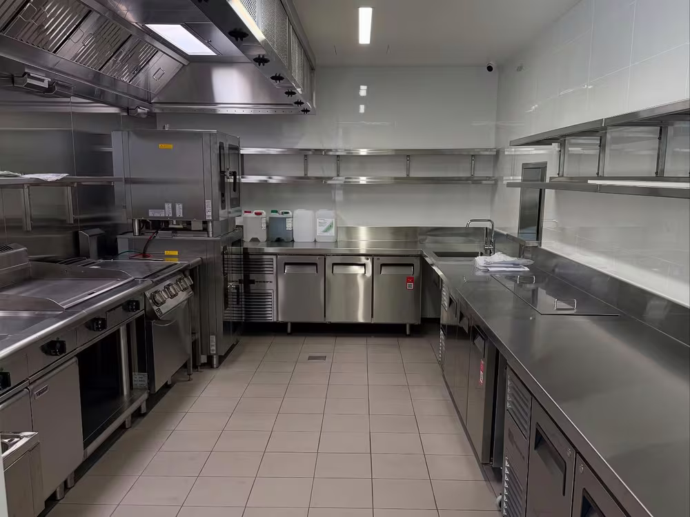 Commercial kitchen with stainless benches and extraction canopies, cleaned by Tier1Clean for handover